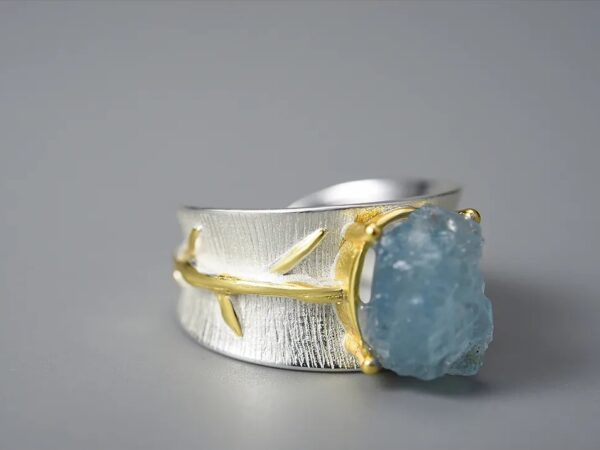 ANILLO AGUAMARINA Este bello anillo está combinado con plata 925 y lo cruza un pequeño hilo dorado.